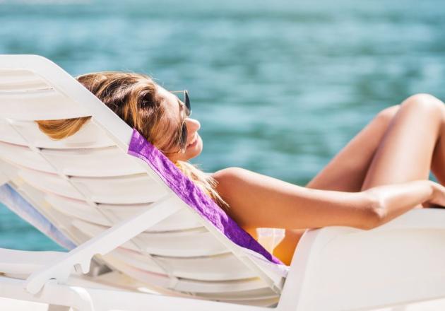 Woman relaxing on a sunbed by calm sea, peaceful and serene atmosphere.